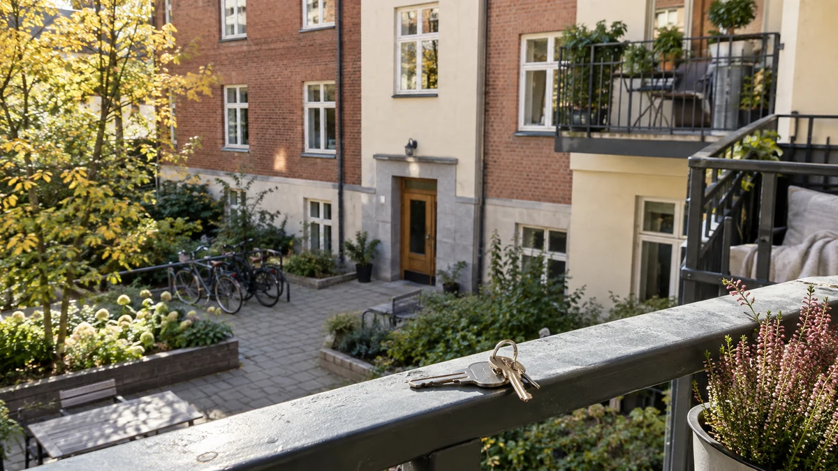 Husnycklar på ett balkongräcke framför en svensk bostadsrättsförenings tegelhus och innergård